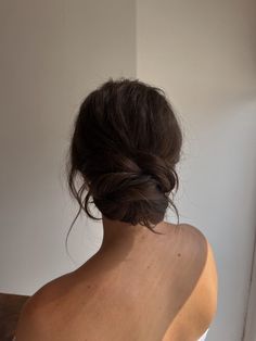 the back of a woman's head, with her hair in a low bun