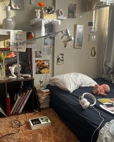 an unmade bed in a small room with many pictures on the wall above it