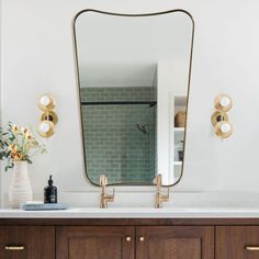 a bathroom vanity with a large mirror and gold faucets on the wall above it