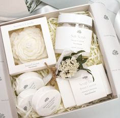 an open box containing soaps, body scrubs and lotion bottles with flowers