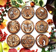 six wooden magnets with designs on them sitting next to leaves and flowers in front of a white background