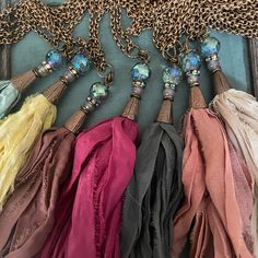 four different colors of scarves are hanging from a chain on a blue tablecloth