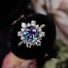 an engagement ring with a blue diamond surrounded by flowers