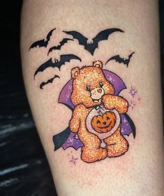 a teddy bear with a pumpkin and bats on it's thigh is featured in this halloween themed tattoo