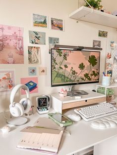 a desk with a computer monitor, keyboard and headphones sitting on top of it