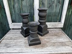 three black vases sitting on top of a wooden table next to a white door