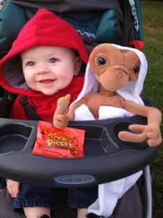 a baby sitting in a stroller with a stuffed monkey on it's back