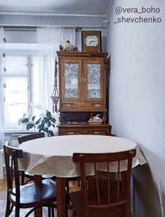 a dining room table and chairs in front of a cabinet with a clock on it