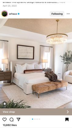 a bed room with a neatly made bed and a chandelier hanging from the ceiling