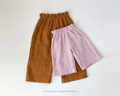 two brown and pink pants sitting next to each other on a white surface with the bottom half off