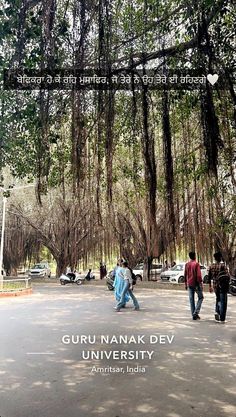 two people walking in the middle of an open area with trees on both sides and text overlay that reads guru nanak dev university