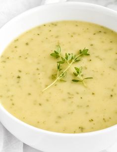 a white bowl filled with soup and garnished with green leaves on top, sitting on a napkin