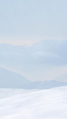 a man riding skis down the side of a snow covered slope with mountains in the background