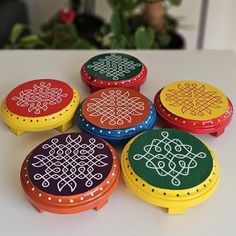 six brightly colored boxes with designs on them sitting on a table next to a potted plant