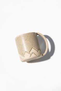 a ceramic cup with a mountain design on the outside and inside, against a white background