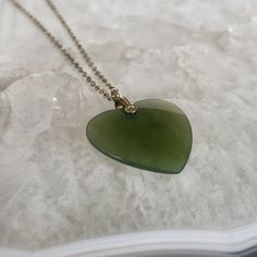 This elegant pendant features a heart-shaped jade stone, measuring 3/4 inches by 7/8 inches, exuding a sense of serenity and tranquility. Jade has long been revered for its metaphysical properties, symbolizing abundance within, fulfillment, contentment, and inner peace. This precious stone carries with it a sense of harmony and balance, making it a cherished talisman for those seeking a deeper connection to themselves and the world around them. The pendant is delicately suspended from an 18-inch Nickel-free Green Heart Necklace, Green Heart-shaped Nickel-free Necklace, Heart Pendant Gold, Elegant Pendant, Junk Drawer, Heart Wedding, Jade Stone, Pendant Gold, Gold Filled Chain