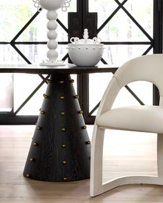 a white chair sitting in front of a table next to a vase on top of a wooden floor