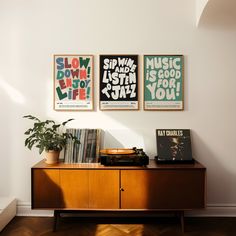 three posters hang on the wall above a record player