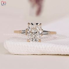 a cushion cut diamond ring on top of a white cloth