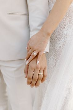 the bride and groom are holding hands with their wedding rings on their fingers as they hold each other's hand