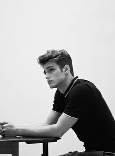 a young man sitting at a wooden table