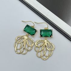 Radiate elegance with our Emerald Green Crystal and Gold Fan-Shaped Charm Dangle Earrings! These handcrafted earrings, featuring lustrous emerald green crystals and sophisticated gold fan-shaped charms, are a perfect blend of timeless glamour and modern flair. The lush green hue of the crystals alongside the striking gold charm adds a rich, luxurious touch to any outfit. Ideal for both day-to-night transitions and special occasions, these earrings offer a unique statement of style and elegance. Formal Green Earrings With Metal Plating, Green Plated Earrings For Formal Occasions, Formal Green Plated Earrings, Green Metal Earrings For Wedding, Green Filigree Earrings For Formal Occasions, Green Metal Evening Earrings, Green Pierced Chandelier Earrings For Party, Elegant Green Crystal Earrings For Pierced Ears, Green Crystal Earrings For Pierced Ears