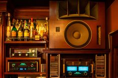 an old fashioned radio sitting on top of a wooden shelf filled with bottles and liquors