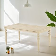 a wooden table sitting in the middle of a room next to a potted plant