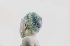 a man's face is covered in green leaves and has his back turned to the camera