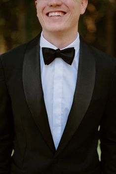 a man in a tuxedo smiles at the camera