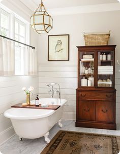 a white bath tub sitting next to a wooden cabinet