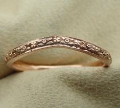 a wedding ring with filigrees and scrolls on the side, sitting on a white cloth