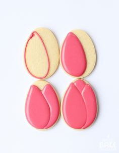 three cookies with pink and yellow icing on top of each cookie, one in the shape of a tear