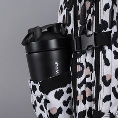 a black and white backpack with a coffee cup in it