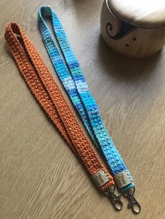 a blue and orange crocheted dog leash on a table next to a wooden bowl