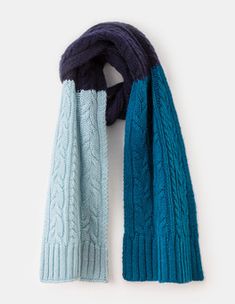 two scarves hanging on a wall, one blue and the other green with cabled ends