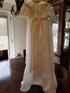 "FREE SHIPPING IN THE U.S. and reduced shipping rates for International orders. This beautiful gown is grandmother's wedding dress conversion, but it can be made new from similar fabric from my shop. Satin bodice with puffed sleeves and a scalloped lace edge. Organza skirt also has the scalloped lace edge. Beautiful large collar in the front with a bow (optional) Satin ribbon ties in the back of the waist. Bridal looping and satin buttons close the back. Matching bonnet included. Gown is made he Cream Floor-length Gown For Ceremony, Regency Style Wedding Gown With Lace Trim, Fitted Gown With Lace Bodice For First Communion, Fitted Lace Bodice Gown For First Communion, Regency Style Empire Waist Wedding Gown, Regency Style Full Length Wedding Dress, Cream Baptism Dress With Fitted Bodice, Fitted Ball Gown For Baptism, Fitted Ball Gown Dress For Baptism