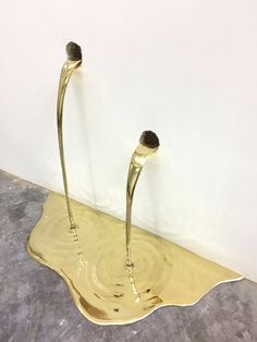 two gold colored vases sitting on top of a metal tray in the middle of a room