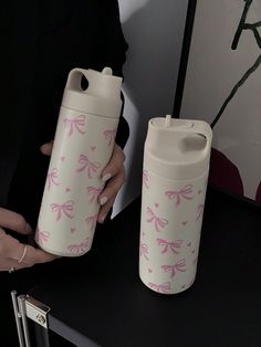 a woman holding a white and pink cup next to a water bottle