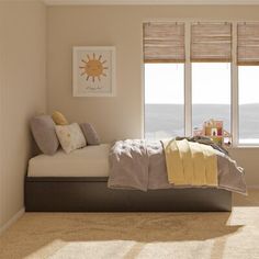 a bed sitting in a bedroom next to two windows with blinds on top of them