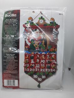 a christmas themed cross stitch kit with santa claus and other holiday items in the package