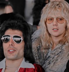 two people with sunglasses on their faces and one wearing a fur coat, are looking at the camera