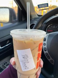 a person holding up a drink in their hand with a price sticker on it