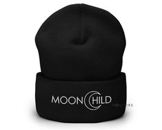 a black beanie hat with the moon child logo in white on it, against a white background