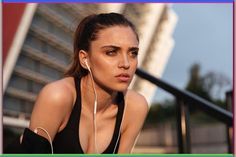 a woman with ear buds on her ears is looking at the camera and listening to music