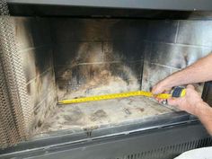 a man is measuring the width of a fireplace