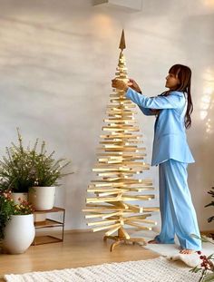 a woman standing next to a wooden christmas tree