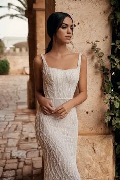 a woman in a white dress standing next to a wall