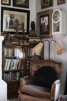 a living room filled with lots of books and pictures on the wall next to a chair