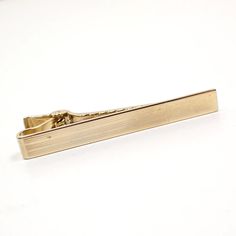 Anson tie clip with lightly striped design and a shiny rectangular end. Size: 2 1/8" in size. Type: Pre Owned Mid Century Vintage from the 1960's. Condition: Tiny spot on front when viewed under magnification. Clip in good working condition. Materials: Gold plated metal. Markings: Marked Anson on the back. Elegant Gold Rectangular Suit And Tie Accessories, Vintage Tie, Tie Clips, Tie Tack, Mid Century Vintage, Tie Accessories, Suit And Tie, Stripes Design, Tie Clip